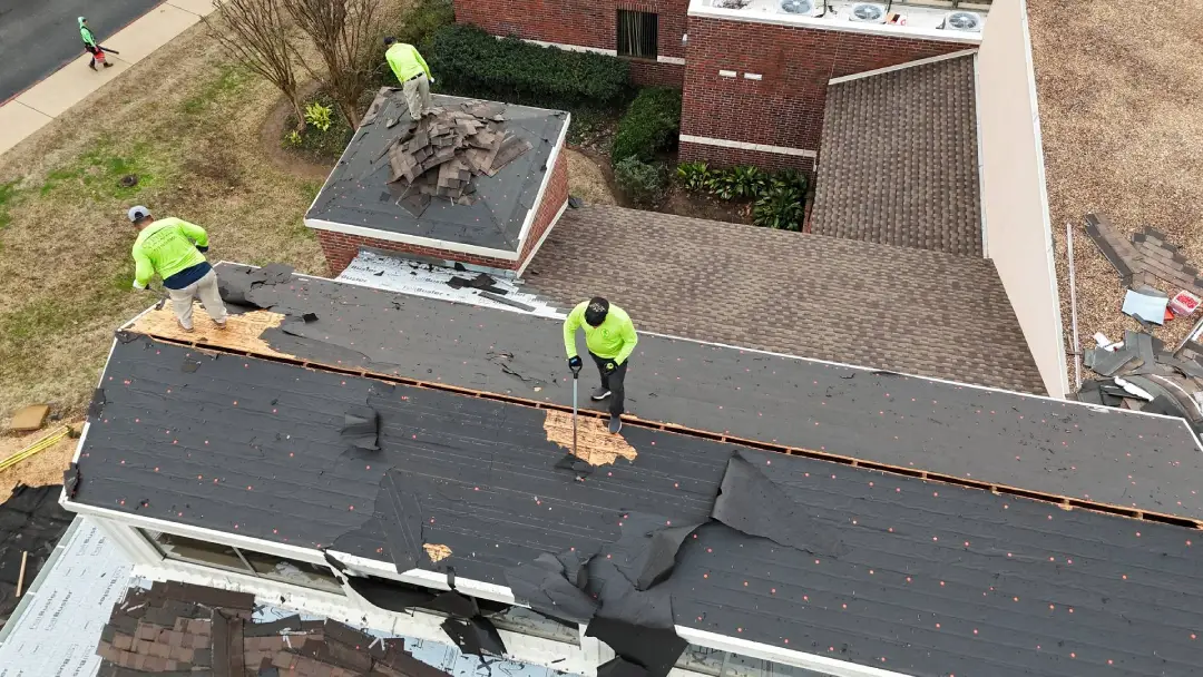 Roofing company workers replacing shingles on residential roof